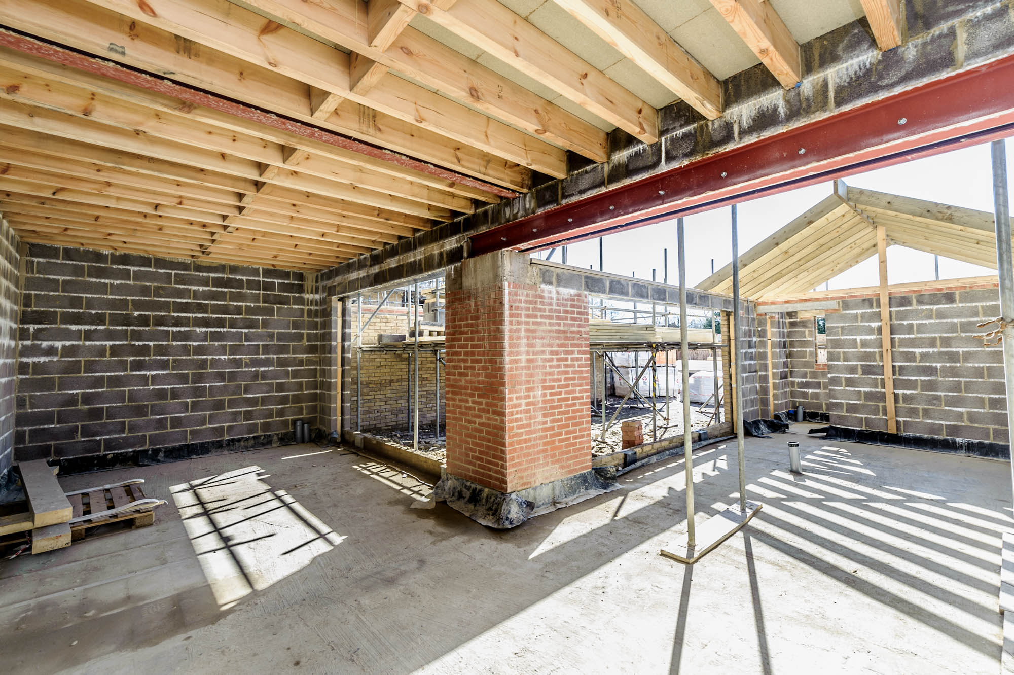 A photo of the interior of a house during the building stage showing beams, bricks and lintels