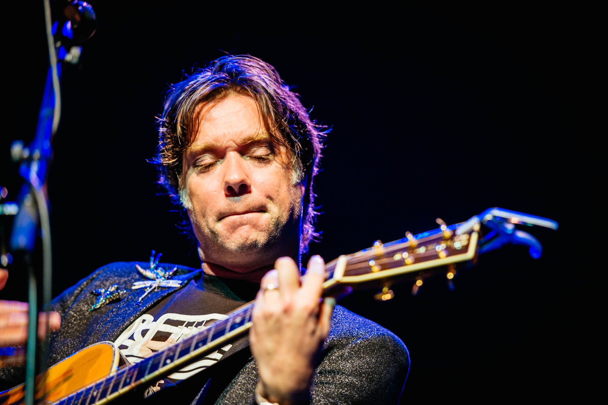 A photo of Rufus Wainwright at the Festival of Voice onstage playing a guitar